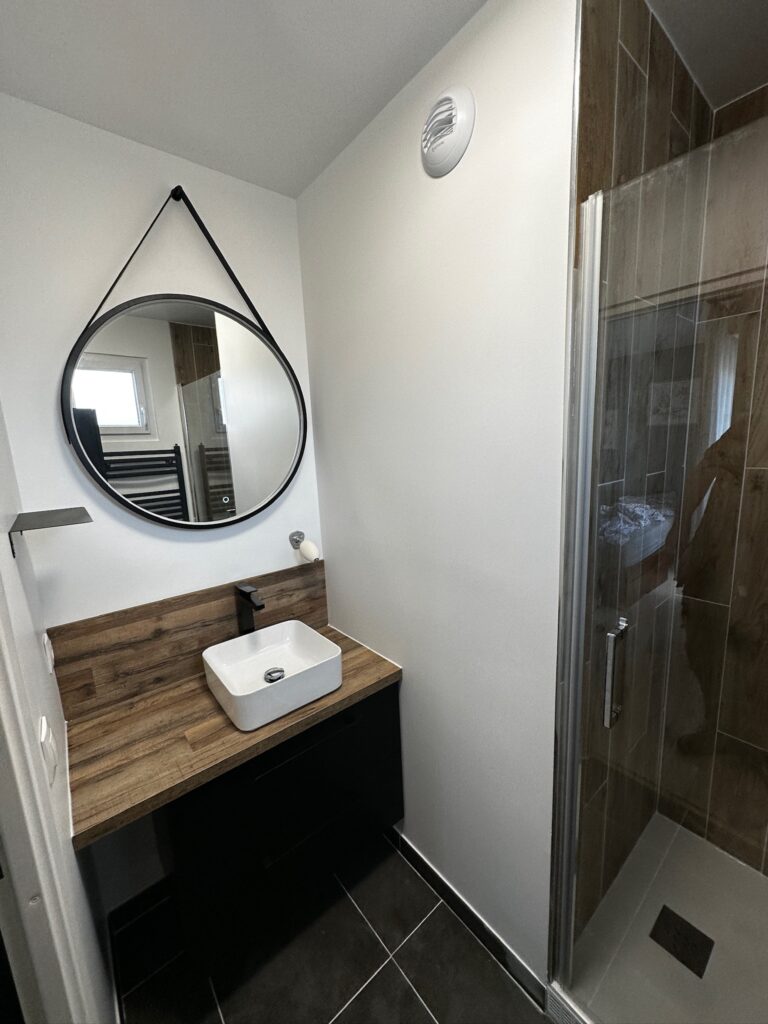 Meuble vasque et miroir rond dans une salle de bain rénovée